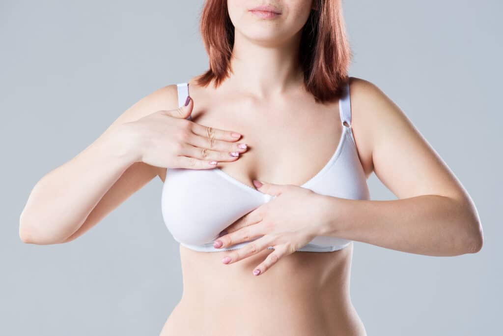 Breast test, woman examining her breasts for cancer, big natural boobs on gray background Breast Reduction Tuscaloosa AL