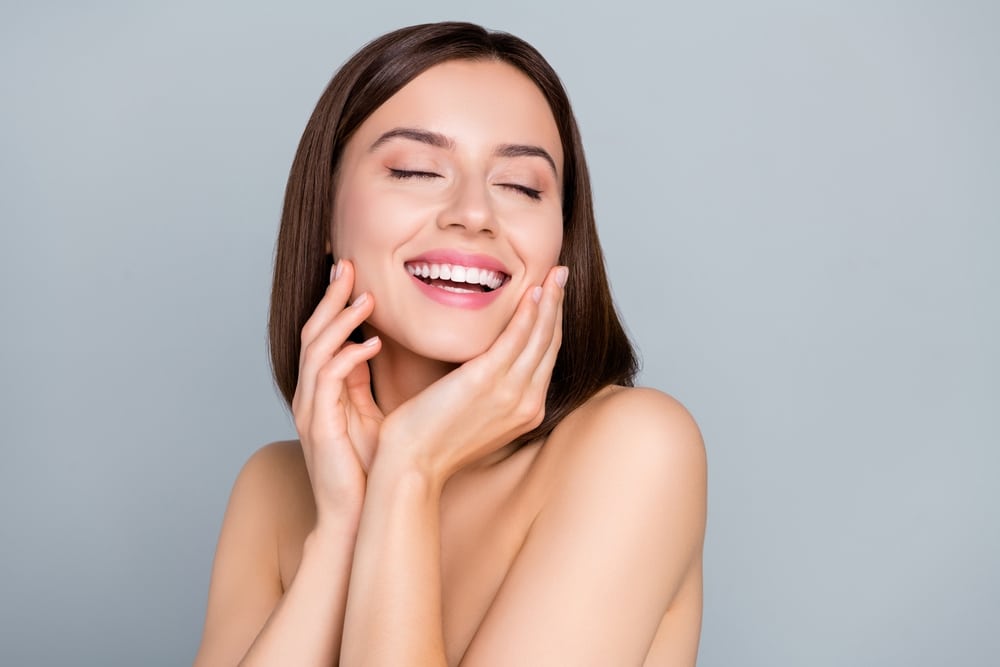 Woman laughing touching her face after getting dermal fillers in Tuscaloosa, AL